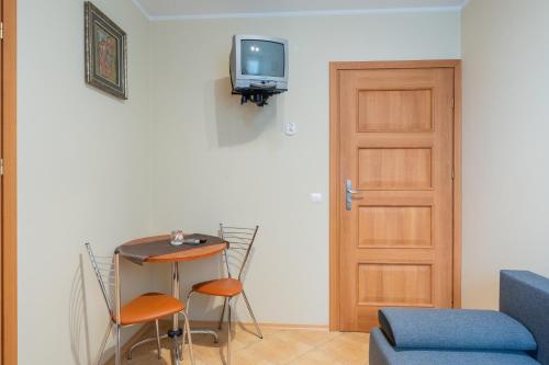 Habitación con puerta, mesa y TV. en Słoneczna Przystań (pokoje z łazienkami), en Dźwirzyno