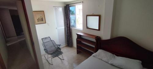 een slaapkamer met een bed, een spiegel en een stoel bij Canadian House Tolú in Tolú