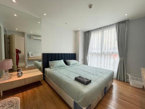 a bedroom with a bed and a table and a window at Grand Caribbean Resort Pattaya in Pattaya South