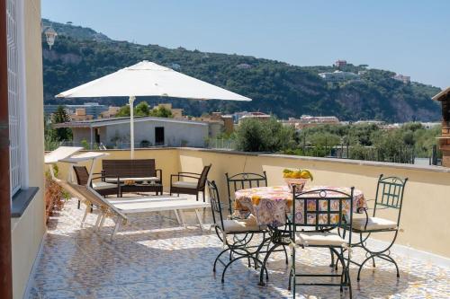 une terrasse avec une table, des chaises et un parasol dans l'établissement Sorrento Realty Holidays Pinnidys House, à Sorrente