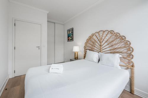 a white bedroom with a large white bed with a wooden headboard at GuestReady - Mystic Subdual in Porto