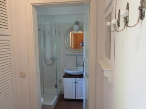ein Bad mit einer Dusche, einem Waschbecken und einem Spiegel in der Unterkunft Ferienwohnung Kurparkhaus 19c Wyk in Wyk auf Föhr