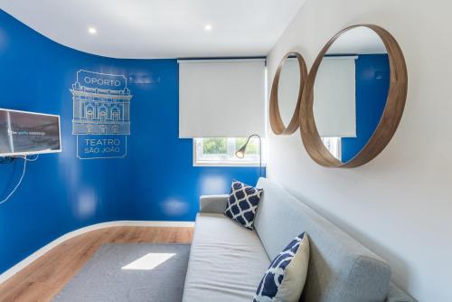Sala de estar azul con sofá y espejo en GuestReady - Theater Apartment en Oporto