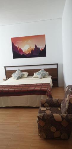 プレンヌ・マニェンにあるRoyal Residencyのベッドルーム1室(ベッド1台、椅子、絵画付)