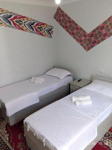 two beds in a small room with white sheets at Nur-Niso Guest House in Bukhara