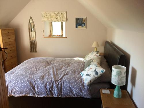 a bedroom with a bed and a table with a lamp at The Laurels in Westwood