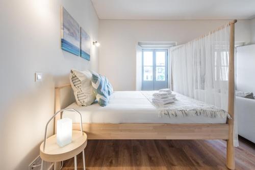 - une chambre blanche dotée d'un lit avec un cadre en bois dans l'établissement GuestReady - Bay Watch, à Porto