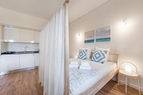 Il comprend une chambre blanche avec un lit et une cuisine. dans l'établissement GuestReady - Bay Watch, à Porto