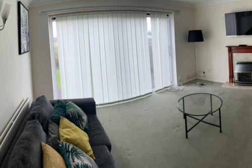 a living room with a couch and a glass table at 3 Bed House with free parking in Wolverhampton