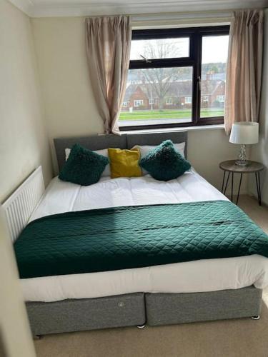 a bedroom with a bed with green and yellow pillows at 3 Bed House with free parking in Wolverhampton
