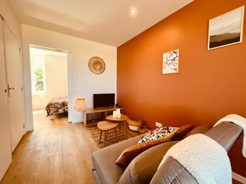 een woonkamer met oranje muren en een bank bij Le Sweet Terracotta in Montluçon
