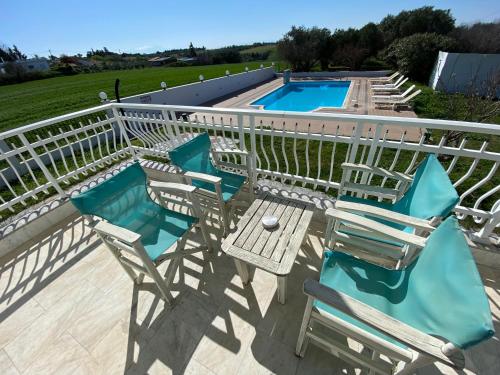 een groep stoelen en een tafel naast een zwembad bij Villa Blue Apartments in Agia Triada