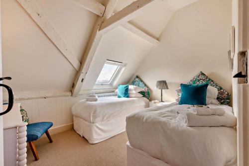 a attic bedroom with two beds and a chair at Owl Barn in Aston