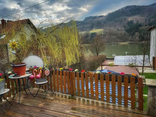 a wooden deck with a fence and a view of a lake at Bungalow Donaublick mit Pool und Garten in Sankt Nikola an der Donau
