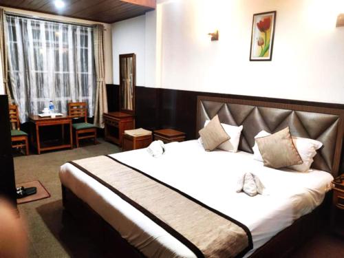 ein Schlafzimmer mit einem großen Bett in einem Zimmer in der Unterkunft Goroomgo Kasturi Palace Darjeeling - Luxury Room with Parking Facilities - Best Seller in Darjeeling
