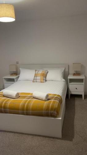 a white bed with two night stands and two tables at Oban Lorne Apartment in Oban