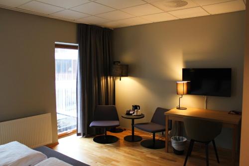 a hotel room with a bed and a desk and chairs at Hotel KRS in Kristiansand