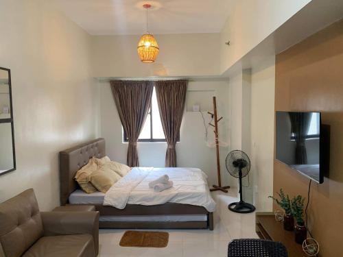a bedroom with a bed and a couch and a television at Brenthill Condo (Ceramic Unit) in Baguio