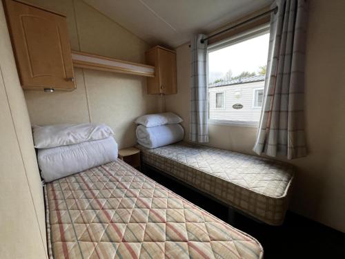 a small room with two beds and a window at Lovely 6 Berth Caravan At Southview Holiday Park Ref 33182s in Skegness