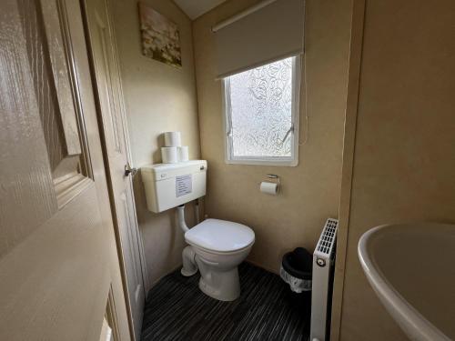 a small bathroom with a toilet and a sink at Lovely 6 Berth Caravan At Southview Holiday Park Ref 33182s in Skegness