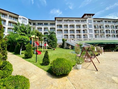 a large building with a playground in front of it at Студио Костови Имоти in Sveti Vlas