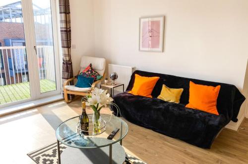 a living room with a black couch and a glass table at Beautiful 2 Bedroom, 2 Bathroom, Free Parking, Milton Keynes City Centre Penthouse Apartment in Milton Keynes