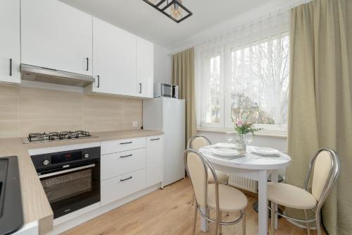 Il comprend une cuisine blanche avec une table et des chaises. dans l'établissement Comfortable Apartment with Balcony in Krakow by Rent like home, à Cracovie