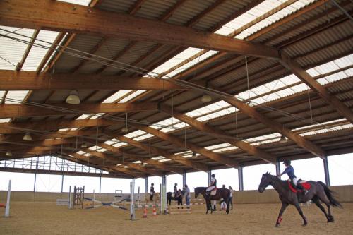two people riding horses in a large barn at Borgo degli Ulivi in Crespellano