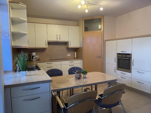 eine Küche mit weißen Schränken sowie einem Tisch und Stühlen in der Unterkunft Ferienwohnung Hof Schäfer in Waldeck