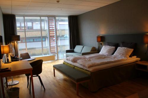 a bedroom with a bed and a chair and a desk at Hotel KRS in Kristiansand