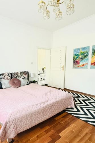 1 dormitorio con cama rosa y lámpara de araña en Apartman Classy Pécs, en Pécs