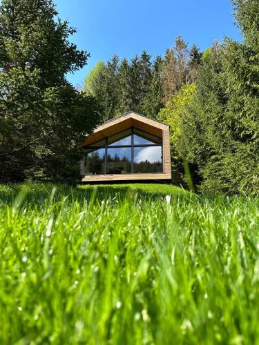 a glass house in the middle of a field of grass at Fenyővölgy Luxus Pihenőház ***** Mátrakeresztes in Matrakeresztes