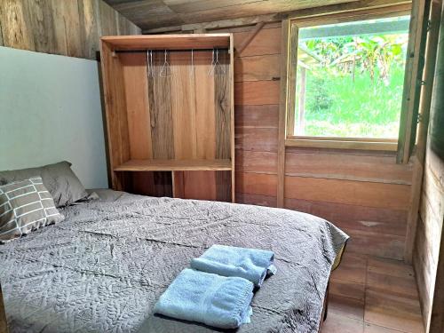 a bedroom with a bed with two towels on it at Rainforest Hut in Archidona