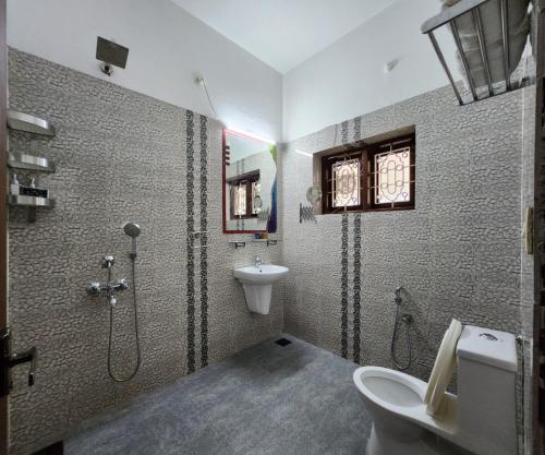 een badkamer met een douche, een toilet en een wastafel bij Bharatham Heritage Inn in Kannur