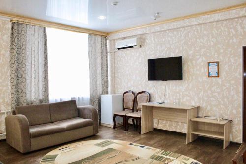 een woonkamer met een bank en een tv aan de muur bij гостиница Павлодар in Pavlodar