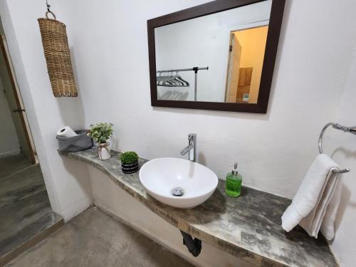 uma casa de banho com um lavatório branco e um espelho. em Casa Bizu em Bacalar