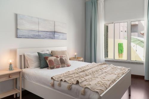 ein Schlafzimmer mit einem großen weißen Bett mit einem Fenster in der Unterkunft Apartamento do Carmo by An Island Apart in Funchal