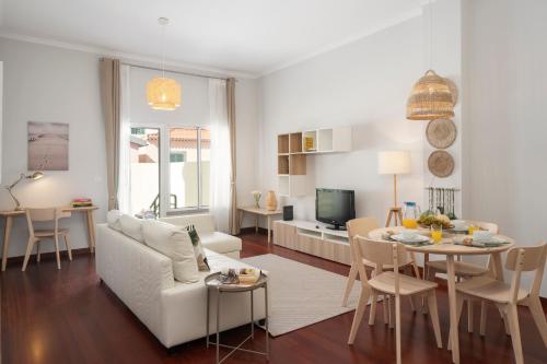 ein Wohnzimmer mit einer weißen Couch und einem Tisch in der Unterkunft Apartamento do Carmo by An Island Apart in Funchal