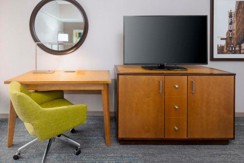 a television on a dresser with a chair and a desk at Hampton Inn and Suites Clayton/St. Louis-Galleria Area in Clayton