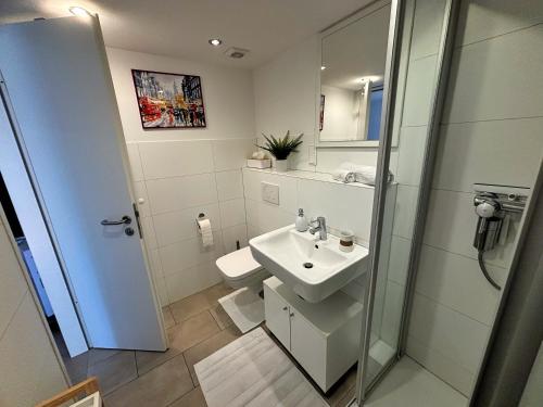 a white bathroom with a sink and a shower at Quiet Garden-View Studio Apartment in Düsseldorf