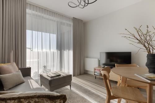 a living room with a table and a dining room at Scala Apartamenty by Moderna Profit- Łąkowa 60E z parkingiem in Gdańsk