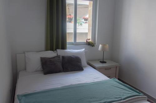 uma cama num quarto com uma janela em Ta Xbiex Cityscape Apartment em Taʼ Xbiex