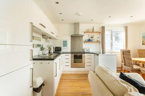 a kitchen with white cabinets and a couch in a room at Fabulous Beach Pad Just 20 Paces From The Sea in Mawgan Porth