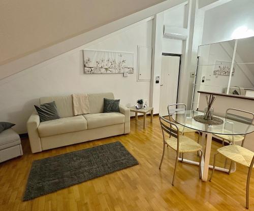 uma sala de estar com uma mesa de vidro e um sofá em Stazione Porta Susa Nest Torino em Turim