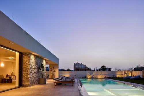 a house with a swimming pool and a patio at Manza Villa in Sfakaki