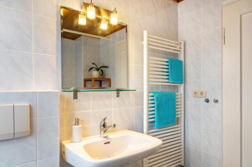 ein Bad mit einem Waschbecken und einem Spiegel in der Unterkunft Ferienwohnung Fischer in Ottobrunn