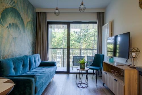 ein Wohnzimmer mit einem blauen Sofa und einem TV in der Unterkunft Baltic Seasons by Alluxe Boutique Apartments in Rogowo