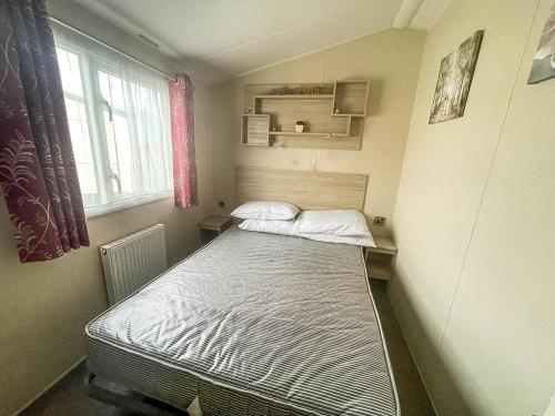 a small bedroom with a bed in a room at Lovely Caravan With Decking Wifi At Dovercourt Park, Essex Ref 44003bv in Great Oakley