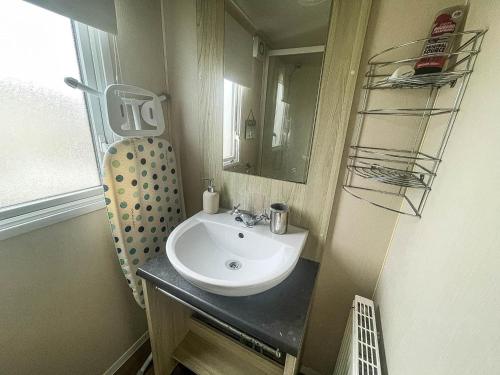 y baño con lavabo y espejo. en Lovely Caravan With Decking Wifi At Dovercourt Park, Essex Ref 44003bv, en Great Oakley