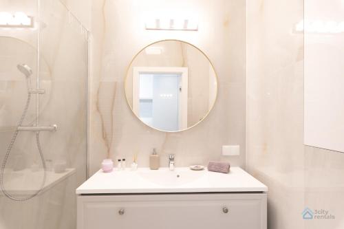 Baño blanco con lavabo y espejo en Garden Studio by 3City Rentals en Gdynia